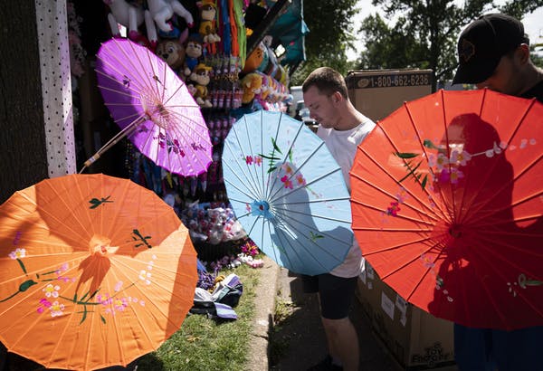 Brenden Lee and Vick Ramirez set up umbrellas for a toy and stuffed animal stand called We Dazzled on Wednesday, the day before the Minnesota State Fa